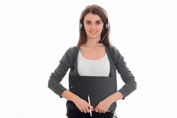 Hermosa chica joven en auriculares y chaqueta gris mira a la cámara y sonríe sosteniendo Tablet — Foto de Stock