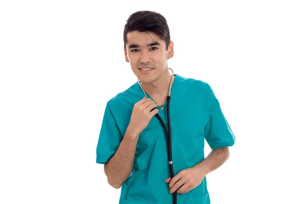 Un joven médico vestido de azul con estetoscopio sonríe y mira a una cámara — Foto de Stock