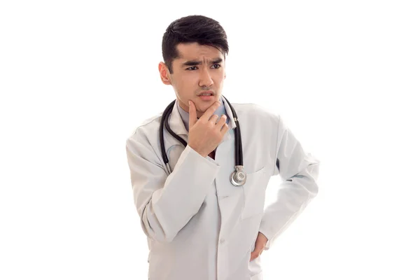 Un médico joven con una bata blanca de laboratorio con un estetoscopio mira cuidadosamente hacia —  Fotos de Stock