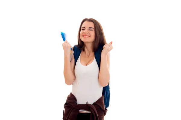 Счастливая юная брюнетка-подросток в стильной одежде и рюкзаке на плечах позирует изолированно на белом фоне — стоковое фото