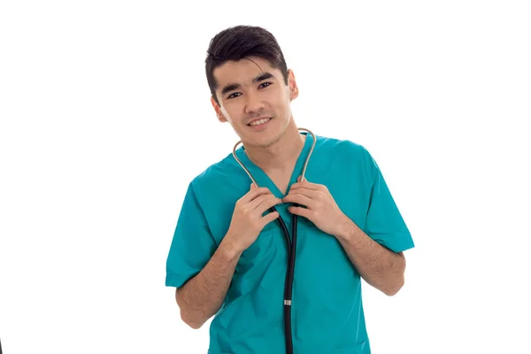 Retrato de belo jovem morena médico masculino em uniforme com estetoscópio posando isolado no fundo branco — Fotografia de Stock