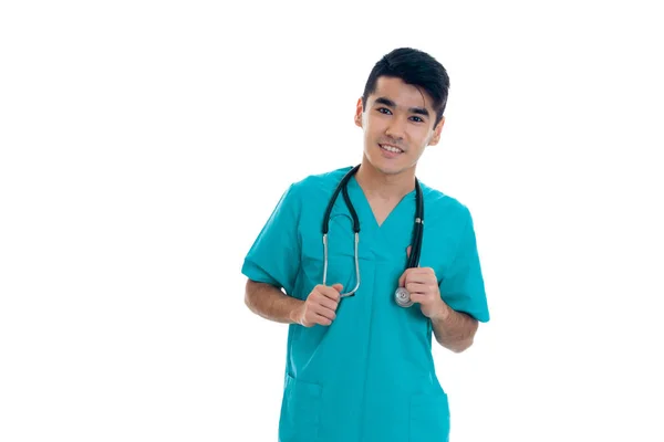 Retrato de jovem morena alegre médico masculino em uniforme com estetoscópio posando isolado no fundo branco — Fotografia de Stock