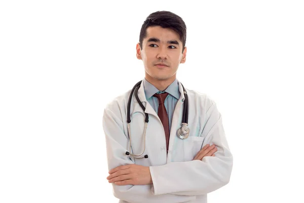 Retrato de morena muito jovem médico masculino em uniforme com estetoscópio posando e olhando para o lado isolado no fundo branco — Fotografia de Stock