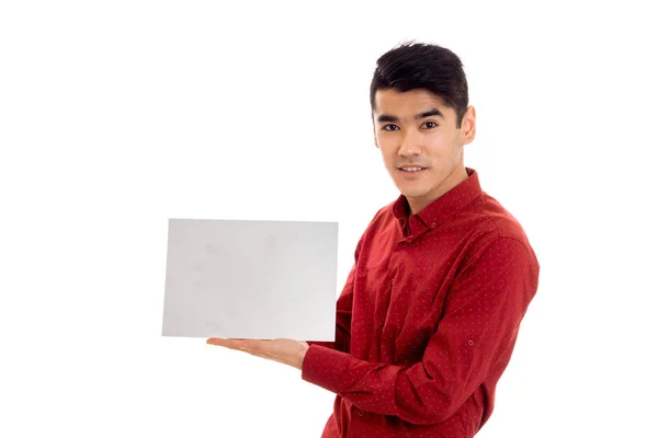 Elegante morena modelo masculino em camisa vermelha posando com cartaz vazio isolado no fundo branco — Fotografia de Stock