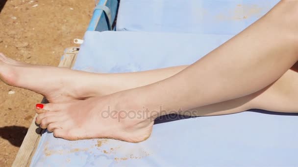 Senhora de maiô vermelho e chapéu de palha tomando banho de sol na praia — Vídeo de Stock