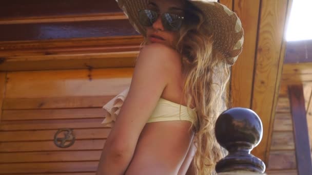 Bonita chica rubia en gafas de sol y sombrero de paja mirando a la cámara hora de verano — Vídeos de Stock