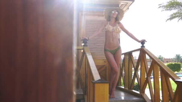 Pani w bikini i straw hat pozowanie na ganku — Wideo stockowe