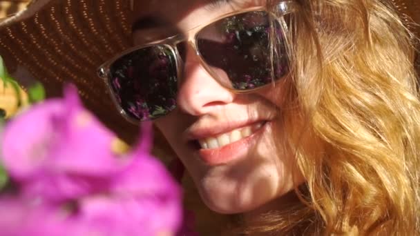 Леди в соломенной шляпе и солнцезащитных очках улыбается на камеру — стоковое видео