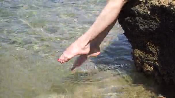 Fille Flops pieds dans la mer se trouve sur le rocher — Video