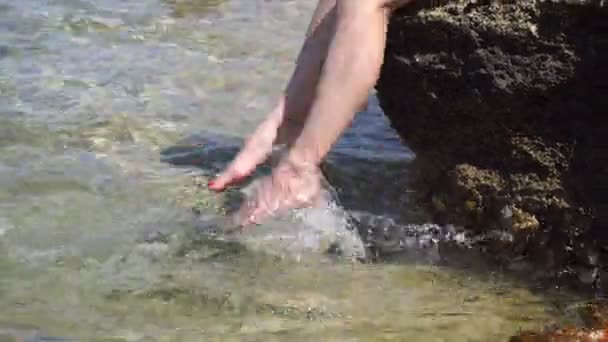 Mädchen sitzt auf dem Felsen und schwimmt mit den Füßen im Wasser — Stockvideo