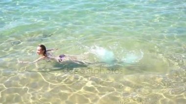 güzel genç kız bir mayo içinde yüzen denize kameraya bakar ve gülümseyen