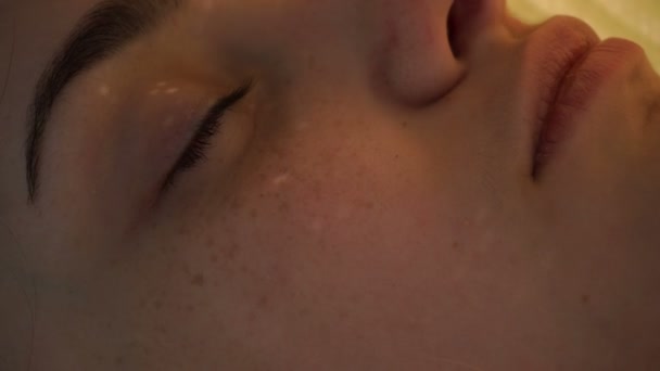 La cara de una joven con pecas que yace con los ojos cerrados — Vídeos de Stock