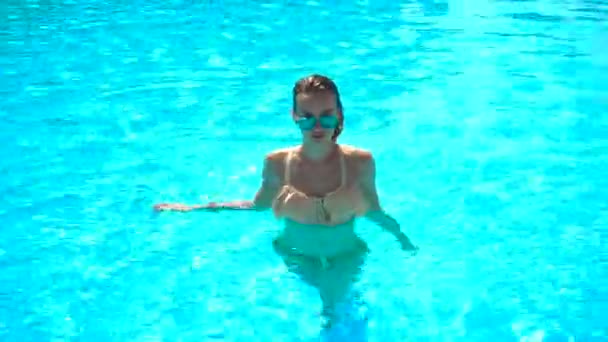 Sexy chica joven en un traje de baño con el pelo mojado y gafas sale de la piscina — Vídeos de Stock