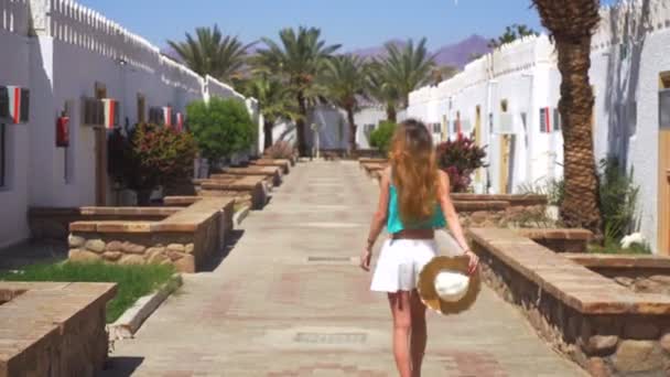 Красивая молодая блондинка ходит вокруг традиционных египетских зданий в яркий летний день — стоковое видео