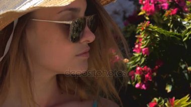 Gözlüklü genç kız bir çiçekli Bush yakınındaki anlamına gelir ve uzak ağır çekim yakın çekim görünüyor