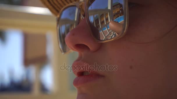 一个年轻的姑娘在通过该眼镜的脸可以看到的游泳池 — 图库视频影像