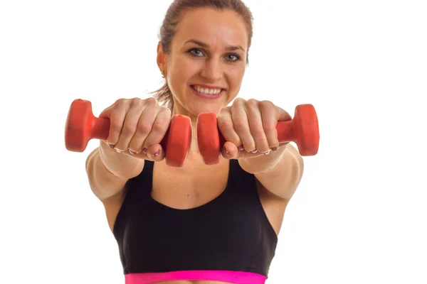 Smiling young girl looks arjamo and stretches vpred dumbbells in hands isolated on white background — Stock Photo, Image