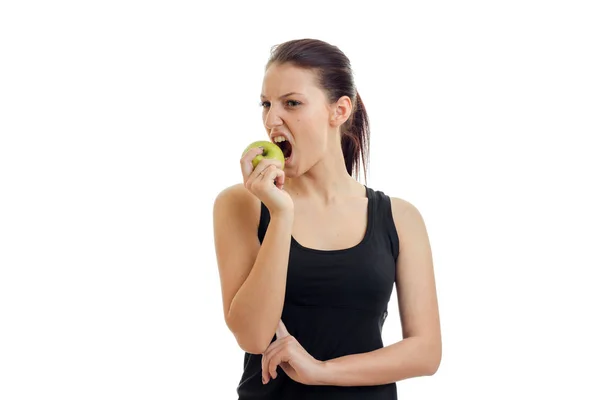 Chica en una camiseta negra es mordido manzana aislado sobre fondo blanco — Foto de Stock