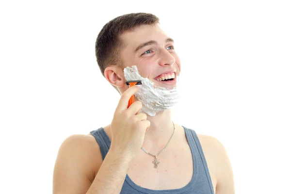 Young gay guy with foam on his face looking sideways and shaves — Stock Photo, Image