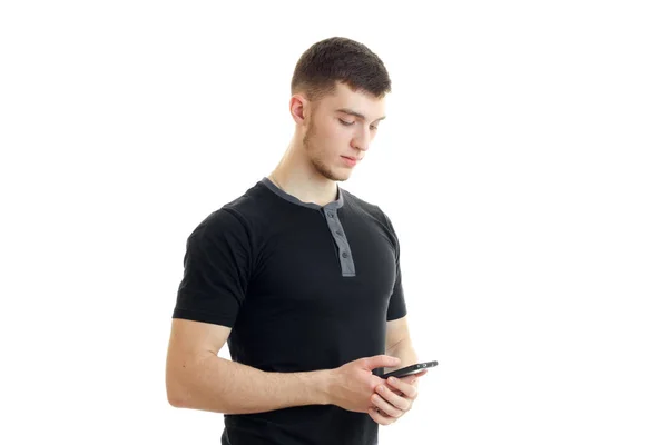 Przystojny, młody facet w czarnej koszuli patrzy na telefon — Zdjęcie stockowe