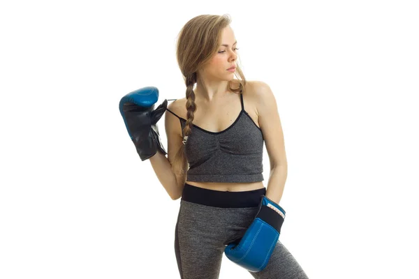 Slim young girl with pigtail stands in boxing gloves and looks toward — Stock Photo, Image