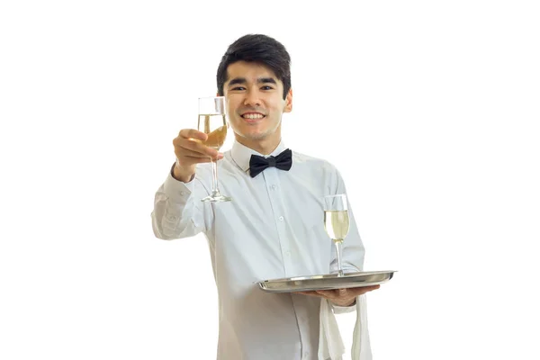 Jonge knappe kelner in een wit overhemd strekt zich vooruit glas wijn en glimlachen — Stockfoto
