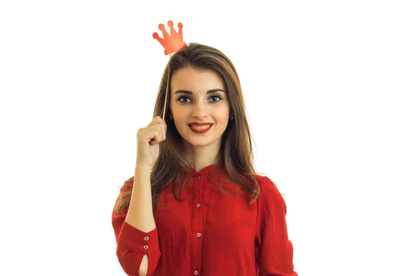 Hermosa joven en un vestido rojo se ve sonrisas rectas y mantiene cerca de accesorios de pelo en forma de la Corona —  Fotos de Stock
