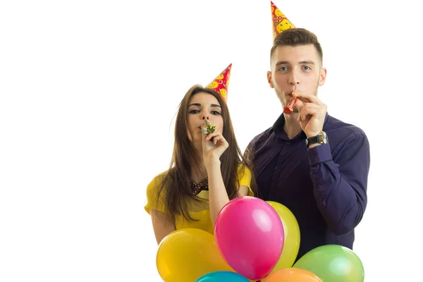 Ung kille med tjej fira födelsedag håller en massa ballonger och horn nära munnen — Stockfoto