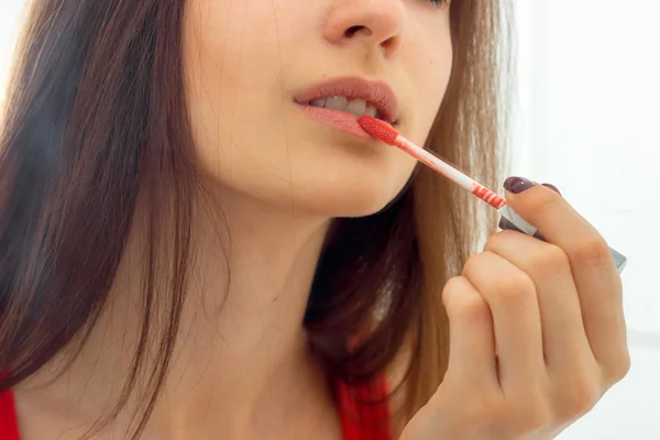 Портрет молодой девушки, которая красит губы красным блеском — стоковое фото