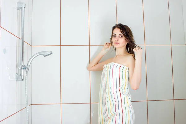 Chica de pie en una bañera en una toalla grande y alisa el cabello — Foto de Stock