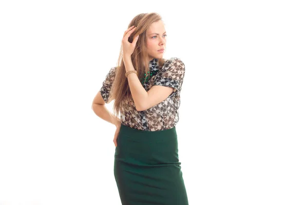 Belle jeune fille en jupe verte et chemisier garde un bras près des cheveux et regarde vers — Photo