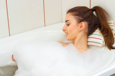 sevimli genç kız gülümseyerek ve köpüklü bir küvette banyo