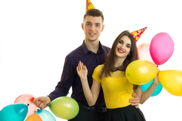 Gay jovem cara com um menina com cones no seu cabeça carregando balões e rindo — Fotografia de Stock