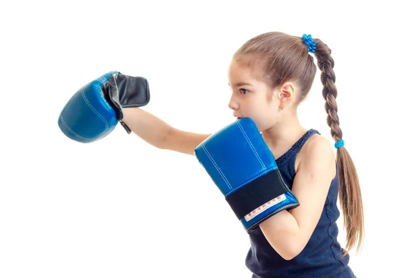 Pequeña niña con una coleta de costado delante de la cámara y mano extendida hacia adelante con grandes guantes de boxeo — Foto de Stock