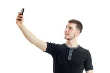 siyah gömlekli genç gülümseyen adam elini yukarı kaldırdı ve bir fotoğraf telefonu yapar