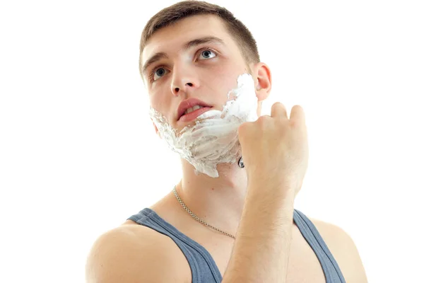 Młody facet patrzy z pianki na twarzy i goli jego zbliżenie broda — Zdjęcie stockowe