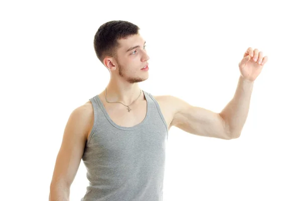 A young guy in the gray shirt looks toward raises his hand and straining muscles — Stock Photo, Image