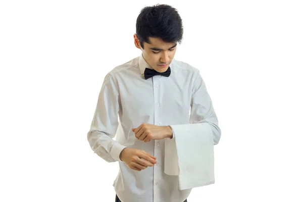 Ein junger Kellner im weißen Hemd neigt seinen Kopf und hält ein Handtuch in der Hand — Stockfoto