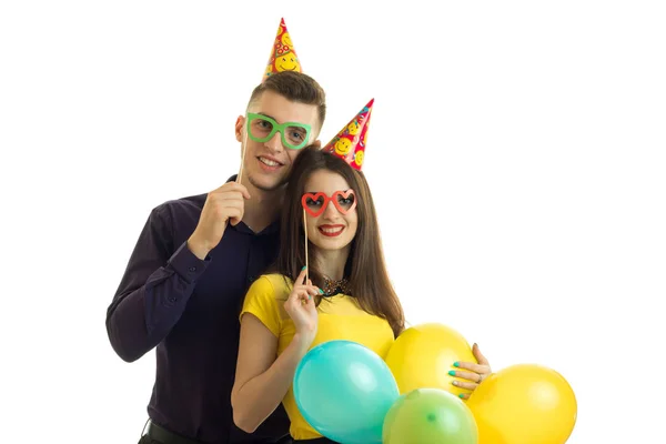 Chico feliz con una chica en gafas de colores llevando globos multicolores — Foto de Stock