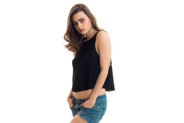 Krásná mladá brunetka v černé tričko stojí bokem a pózuje pro kameru — Stock fotografie