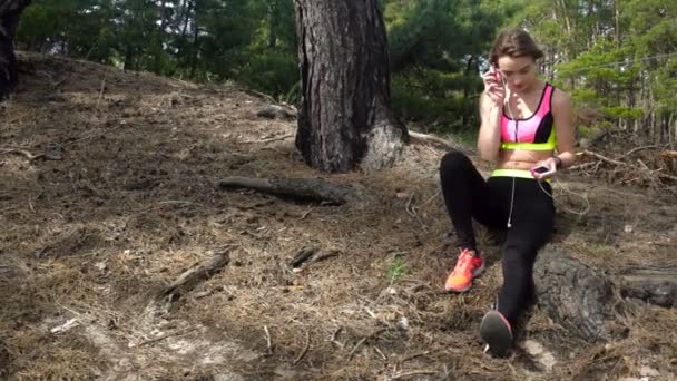 Sportlerin hört Musik im Wald — Stockvideo