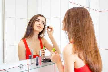 güzel genç kız bir ayna ve boya kirpik önünde duruyor