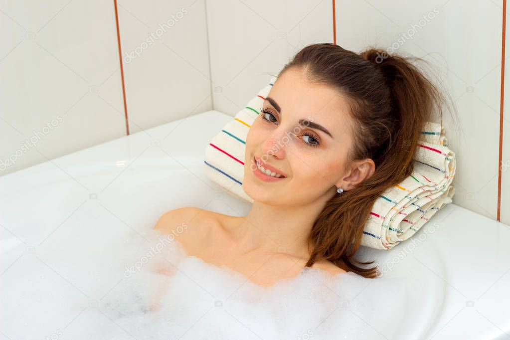 beautiful smiling girl lying in the bath with foam