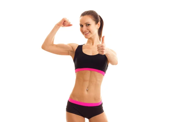 Young smiling girl with press on her stomach in the sports top shows muscle on hand — Stock Photo, Image