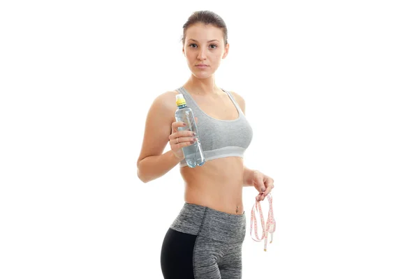 Cute young girl in grey top looks at the camera and holding a water bottle — Stock Photo, Image