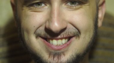 patates cipsi ve kameraya gülümseyen tıraşsız adam yiyor