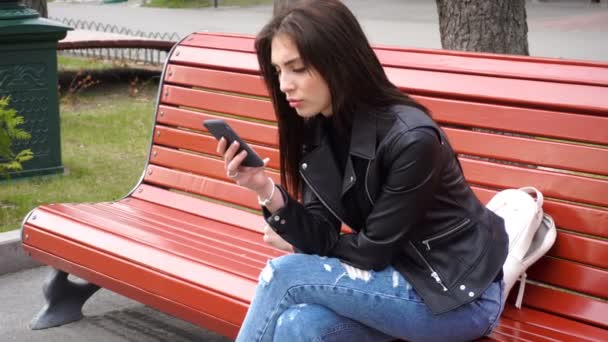 Beautiful girl uses mobile phone outdoors — Stock Video
