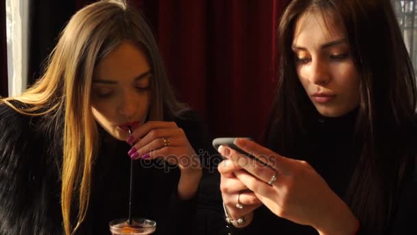 Подруги в кафе смотрят фотографии по телефону и веселятся — стоковое видео