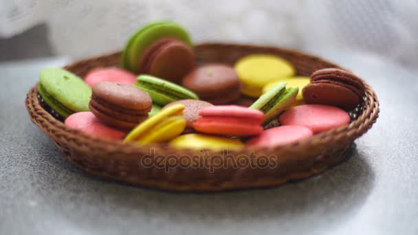 Цветные печенье макарон падает в плетеную пластину — стоковое видео