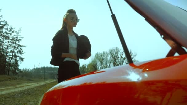 Жінка дивиться під капотом автомобіля на відкритому повітрі — стокове відео
